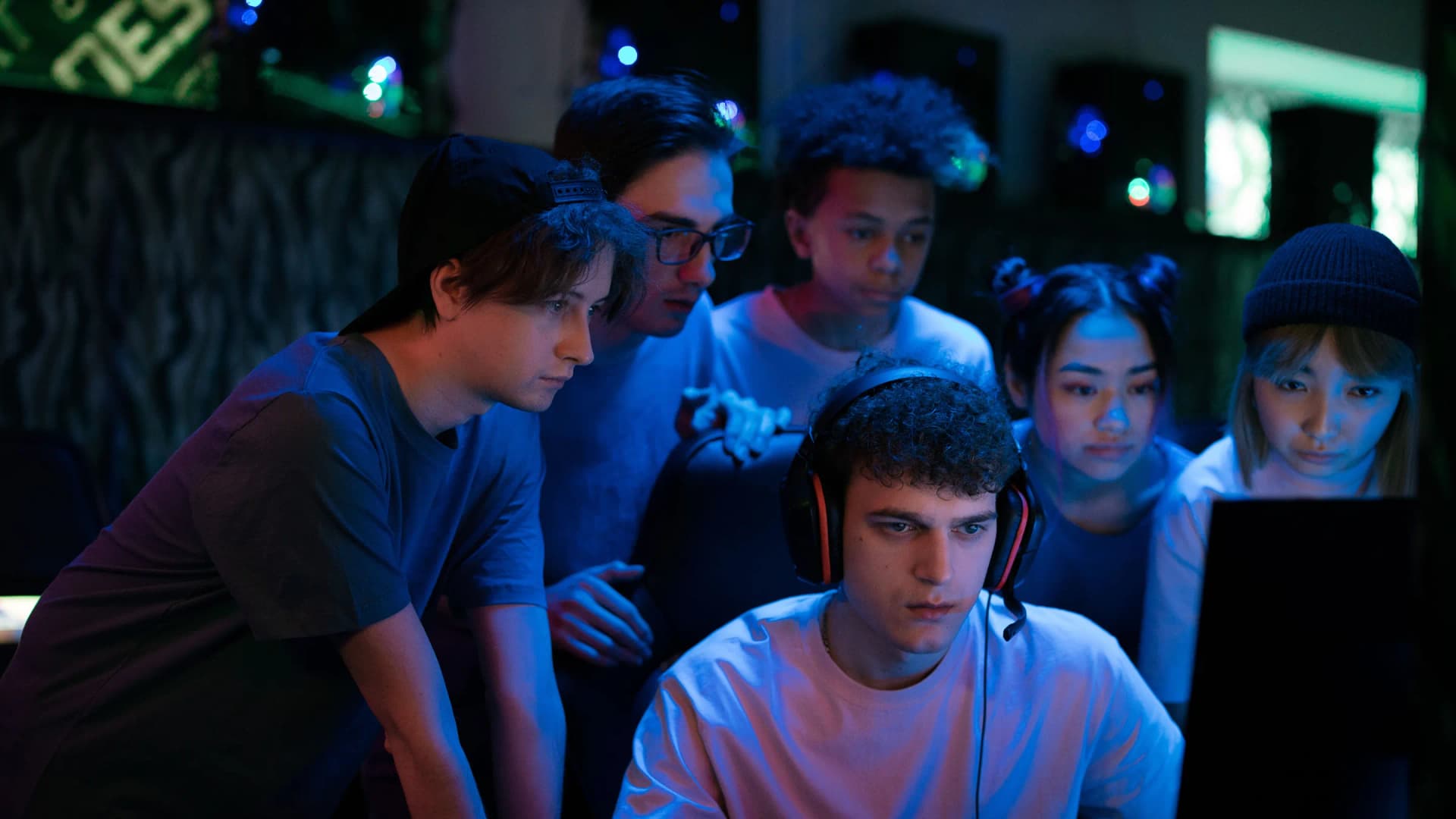 Un grupo de jóvenes alrededor de una pantalla en una sala de neón