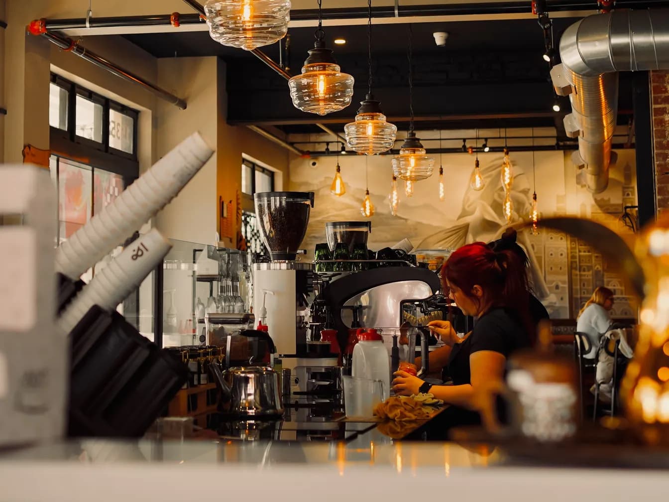 Barista preparando café en la máquina, bajo bombillas cálidas