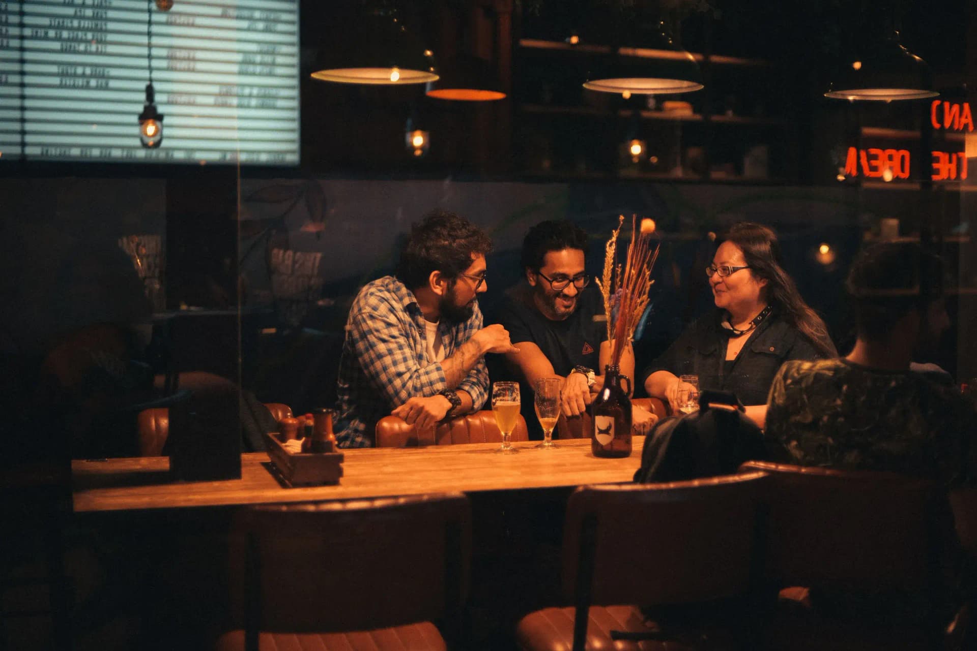 Grupo de amigos conversando en la mesa de un bar en penumbra