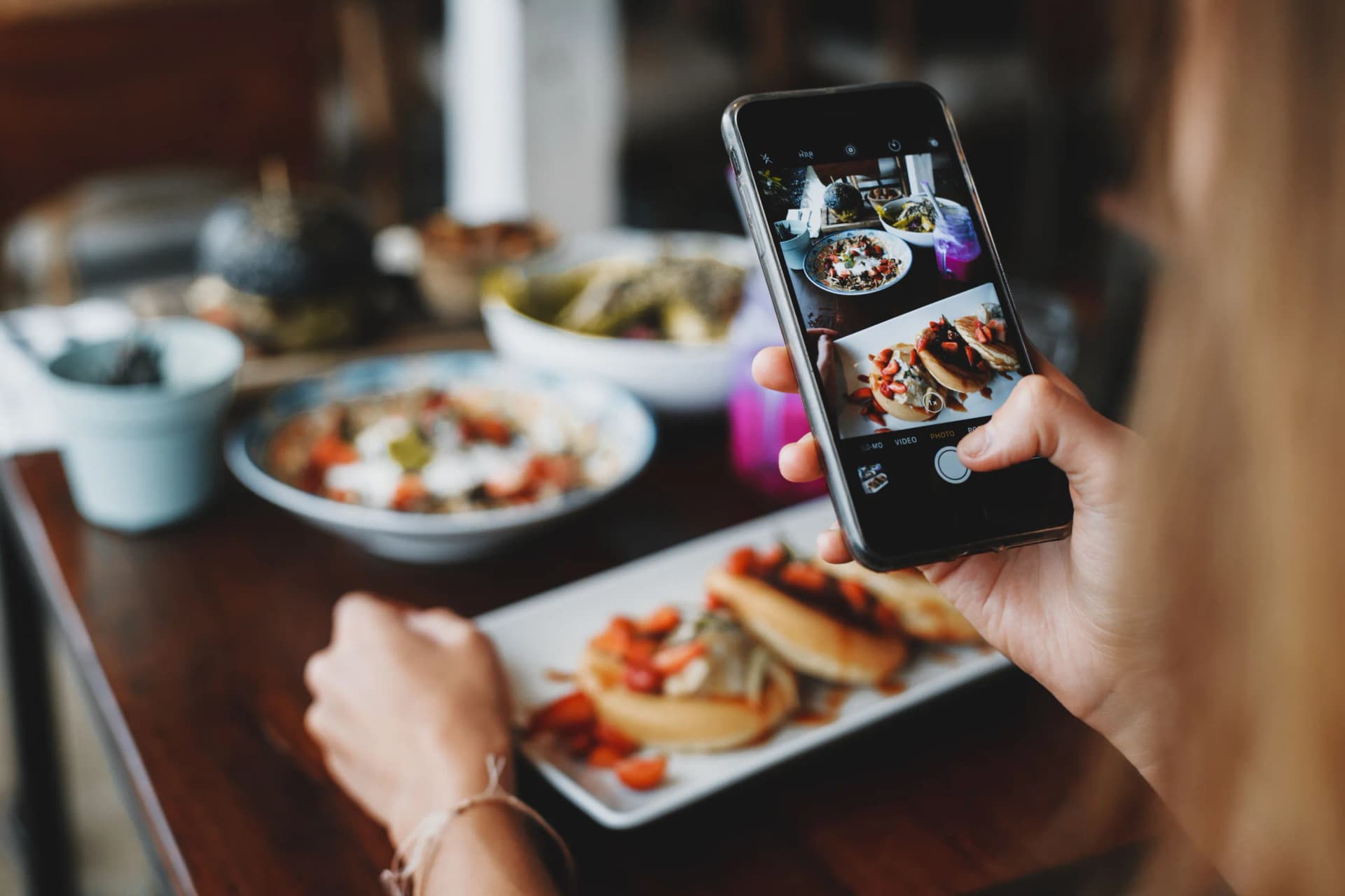 Personas fotografiando una mesa servida con el teléfono